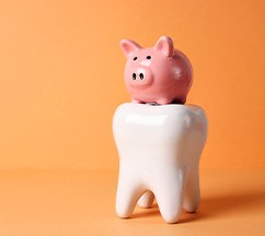Piggy bank on large model tooth with orange background