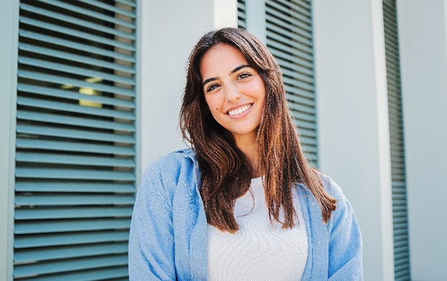 Woman with white teeth smiling while standing outside