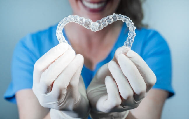Woman holding aligner and model smile with braces