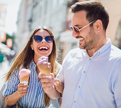 Couple smiling while eating ice cream on walk