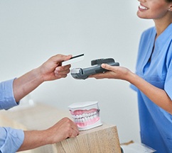 Man handing smiling dental assistant credit card