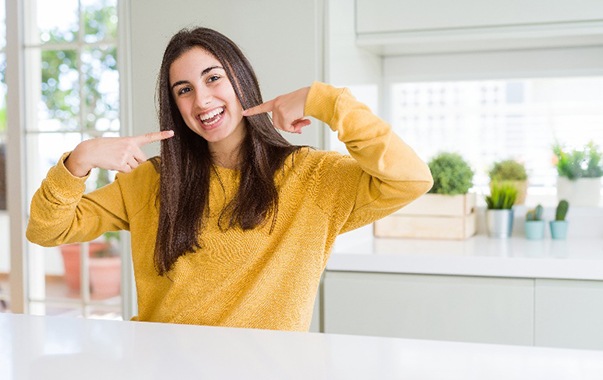 Woman smiling while pointing to white teeth