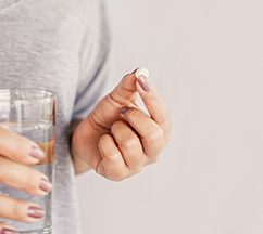 Woman holding a pill and water