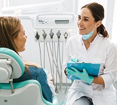 Smiling dentist taking notes on clipboard