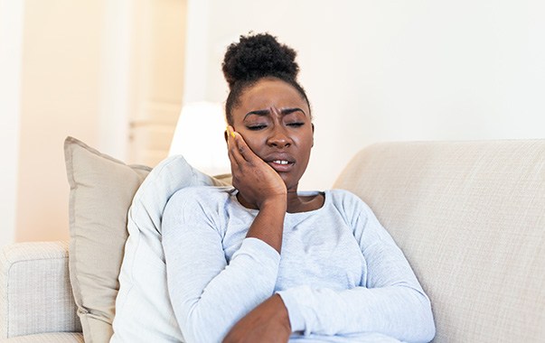 Woman on couch experiencing toothache