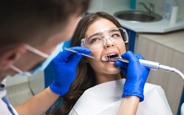 Woman watching dentist who’s performing root canal on her tooth