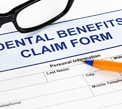 Top of dental insurance benefits claim form with pen and glasses