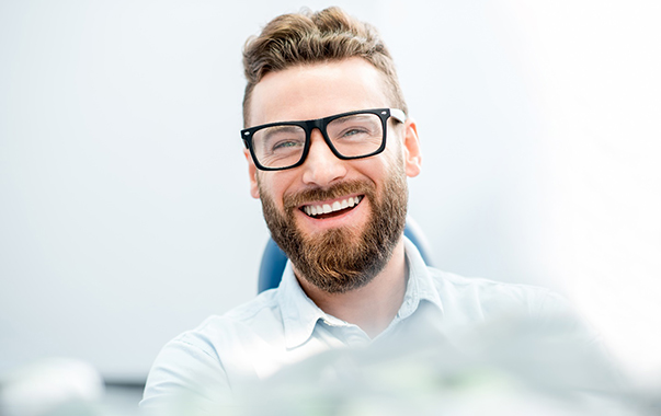 man smiling while sitting in dental chair 