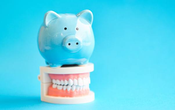 Blue piggy bank sitting on top of a dental model