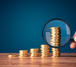 Magnifying glass held over a stack of coins