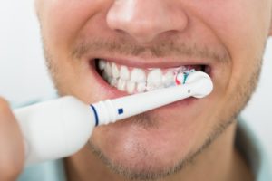 bearded man using electric toothbrush