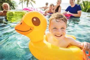 Smiling boy in pool follows tips from Spring Hill emergency dentist