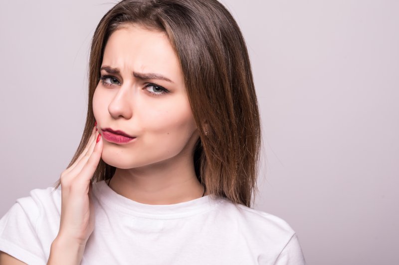 a woman holding cheek with veneers in Spring Hill