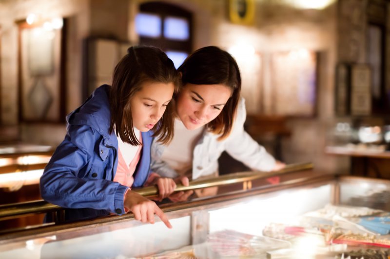 A mother and daughter looking at a display case of old teeth in a museum